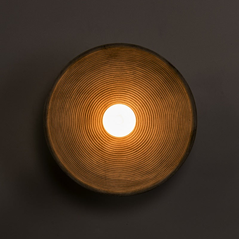 Round ceramic light fixture with a glowing center on a dark background - Lioré® USA