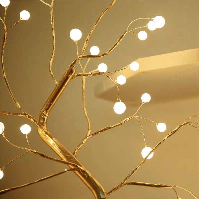 Decorative LED gold branch with string lights against a beige background - Lioré® USA