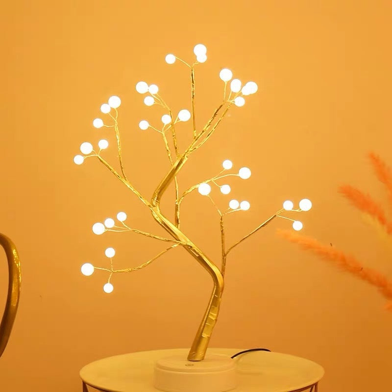 Decorative LED tree with white lights on a gold branch against an orange background - Lioré® USA