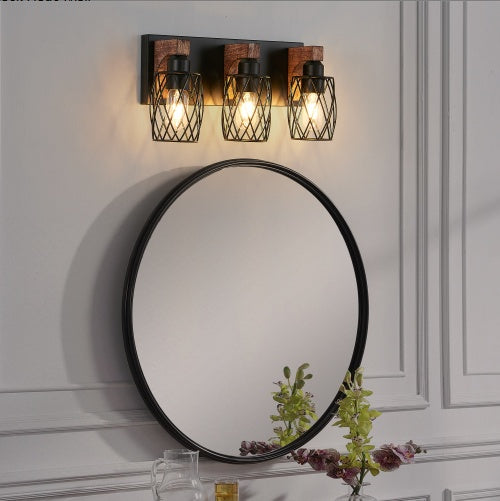 Round mirror with black frame on a wall with three wooden wall lights. -Lioré® USA