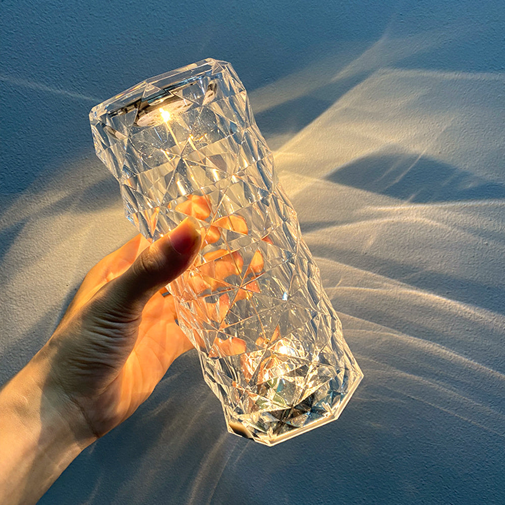 Hand holding a crystal LED lamp with lights inside against a blue background - Lioré® USA