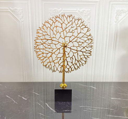 Decorative gold tree sculpture on a black base against a white wall. - Lioré® USA