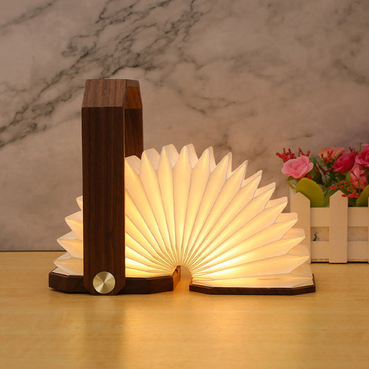 Wooden book-shaped lamp with a warm glow on a marble surface - Lioré® USA