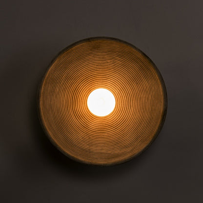 Round ceramic light fixture with a glowing center on a dark background - Lioré® USA
