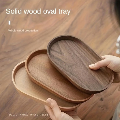 Wooden oval trays with a hand holding one, on a wooden surface. - Lioré®