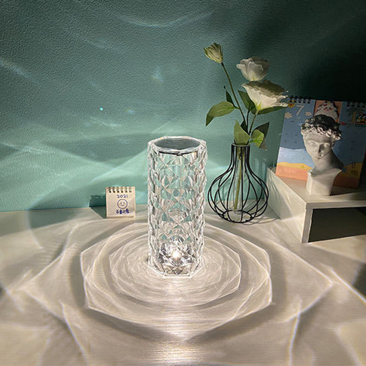 Crystal LED lamp on a textured surface with a calendar and decorative items in the background. - Lioré® USA