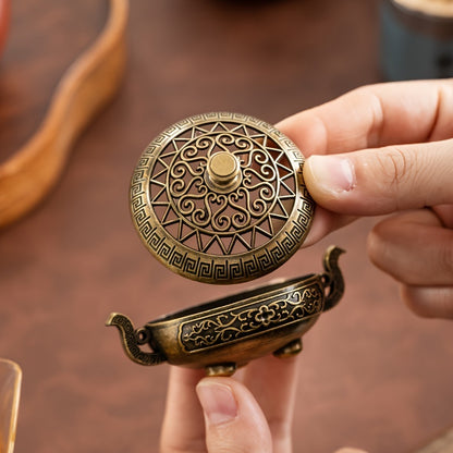 Person holding a decorative bronze object with intricate designs - Lioré®