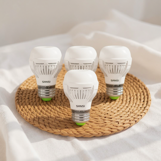 Four SANSI LED light bulbs with green base on a woven mat on a white fabric background - Lioré